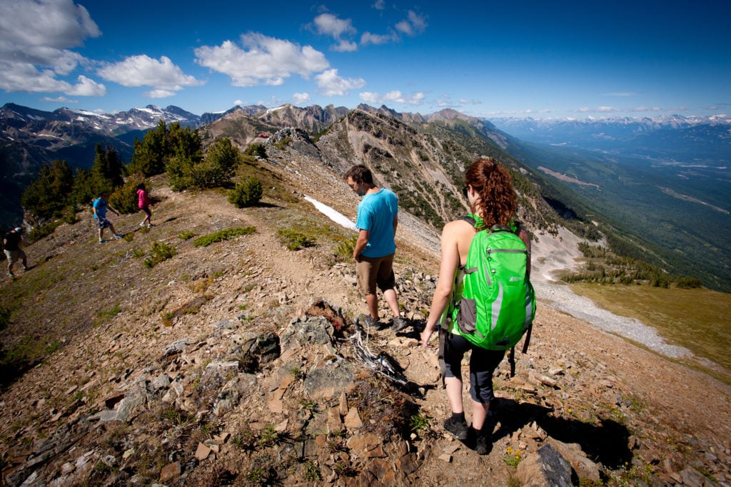 Hikers traverse a rocky terrain on a sunny day.