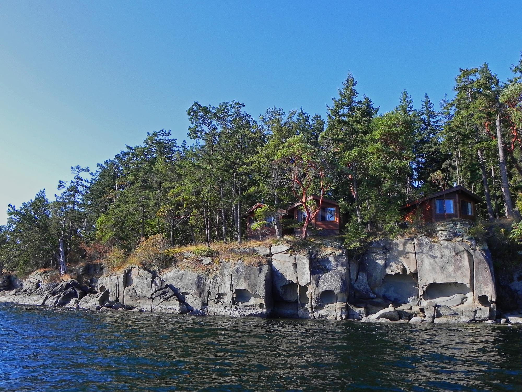 Cottage nestled in a rocky landscape overlooking the water.