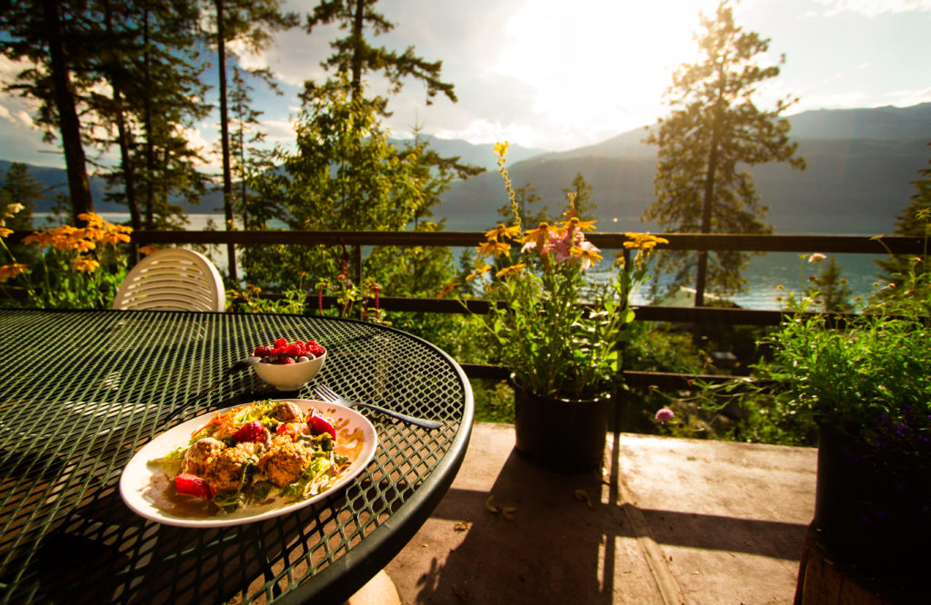 A colourfully plated salad is placed on an outdoor table with views of the mountains.