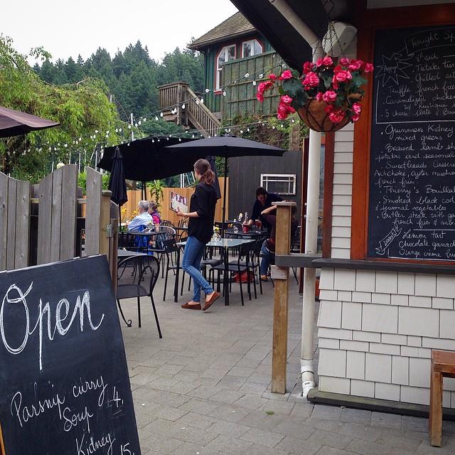 Outdoor entrance to the patio of a restaurant with a chalkboard sign that says “Open”.