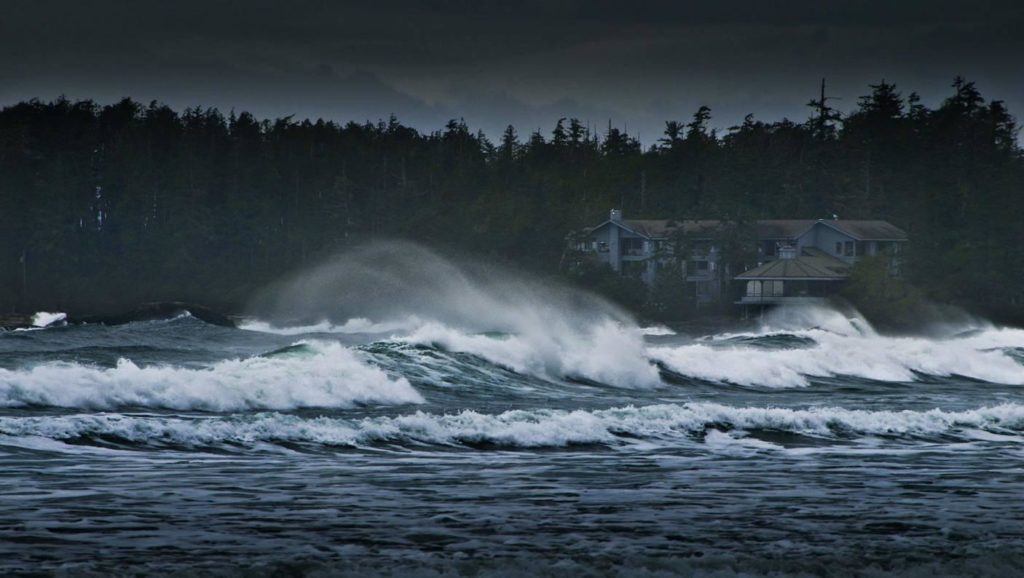 Angry waves crash the shore under a dark sky.