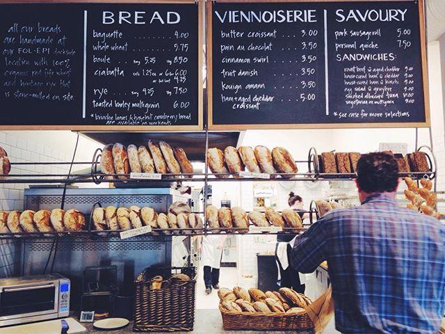Front counter of a bakery with fresh baked breads and a chalkboard menu.