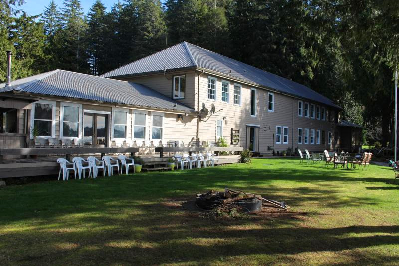 Exterior of a sprawling lodge with a lush lawn on a sunny day.