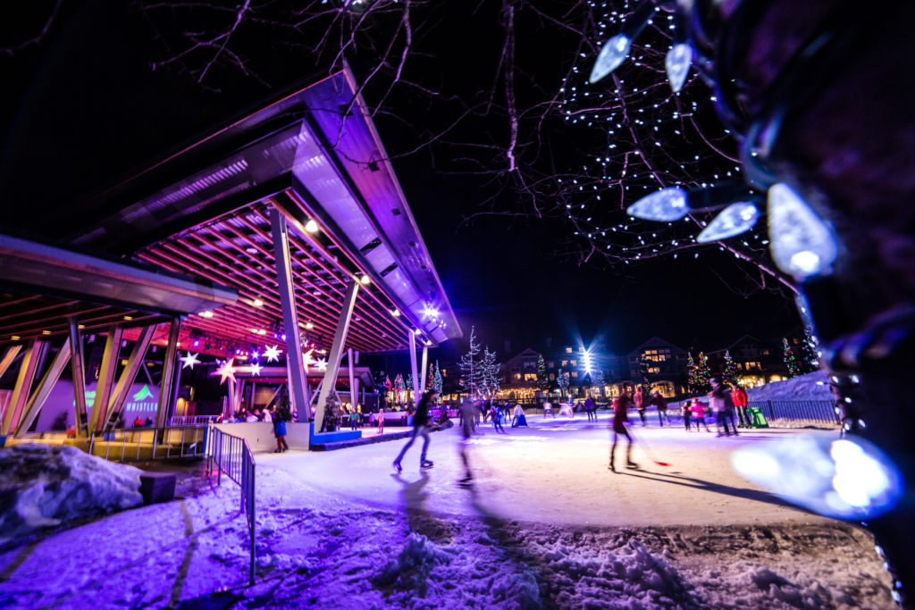 Groups of people skate at an outdoor rink in the evening.