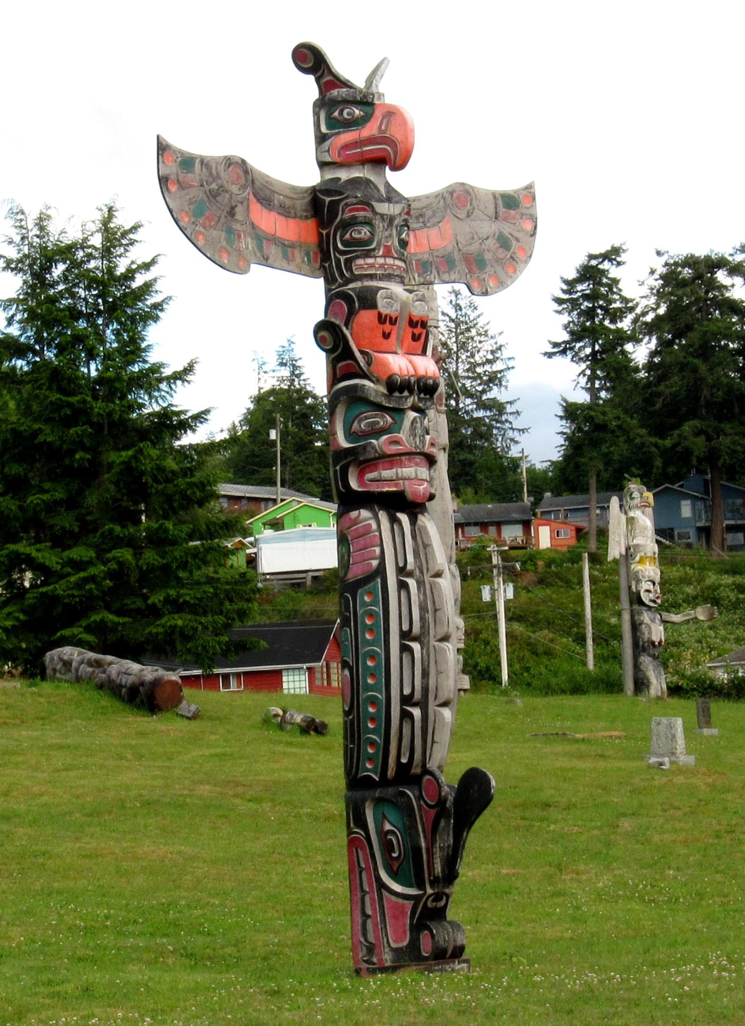 A colourful totem pole erected on a lush green lawn.