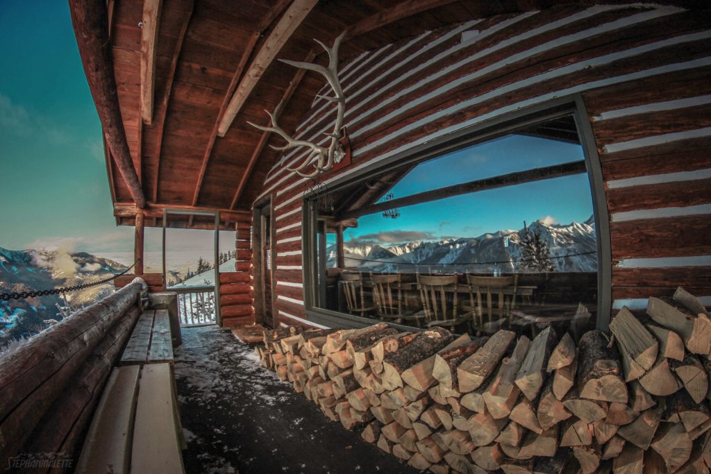 The exterior of a cabin that overlooks a stunning mountain range.