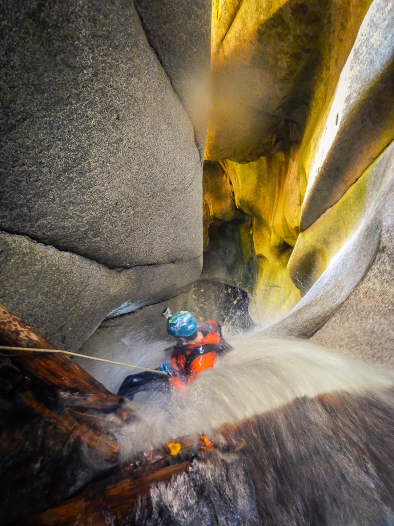 A woman rappels down beautiful granite walls, sculpted by water.