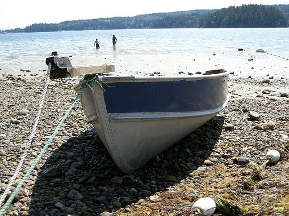 A small boat is pulled up onto a rocky beach.