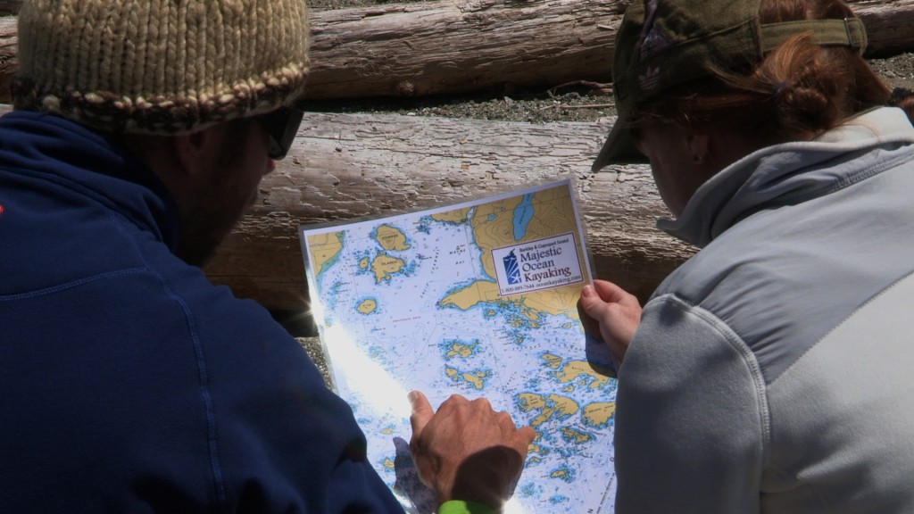 Two men study a Majestic Ocean Kayaking map.