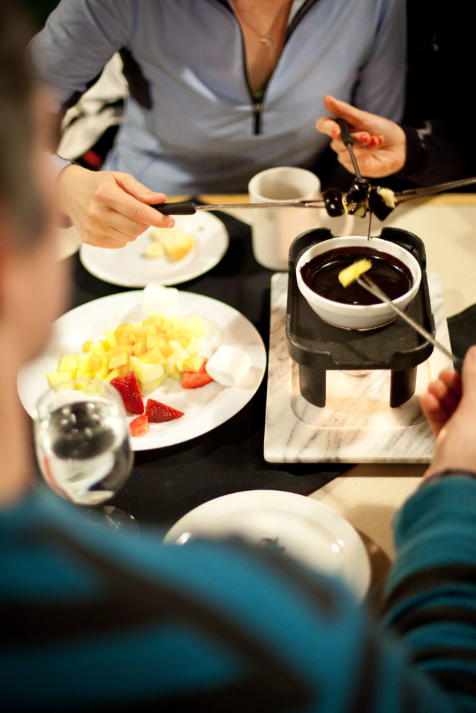 A group of friends enjoy a pot of chocolate fondue.