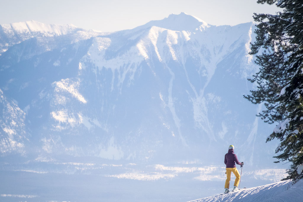 A woman skier stops to take in the snow capped peaks surrounding Kimberley Alpine Resort.