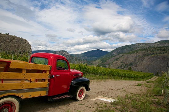 A bright red truck with a wooden box parked on a dirt path on the grounds of Covert Farms.