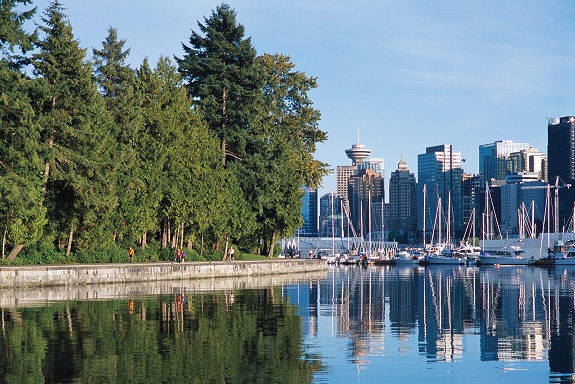 Stanley Park's seawall on the left with the ocean in the centre with Vancouver's skyline reflecting in it. 