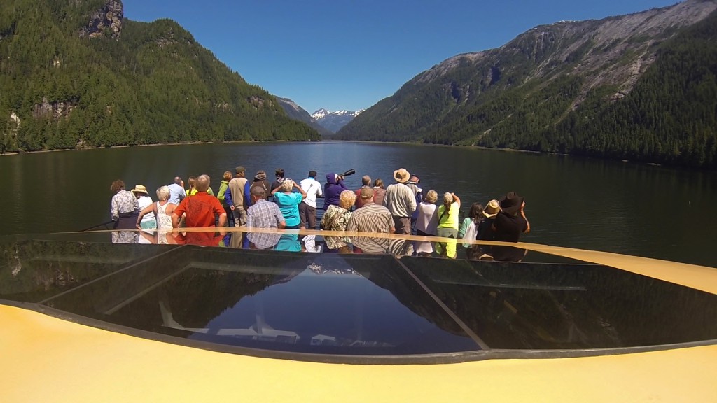 Group of people looking for wildlife from a boat in the Khutzeymateen Grizzly Bear Sanctuary. 