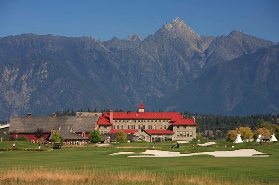 A sprawling resort and golf course nestled at the base of a rocky mountain range.