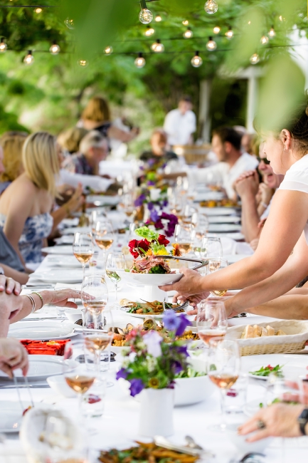 A large group dines alfresco at a beautifully set table.