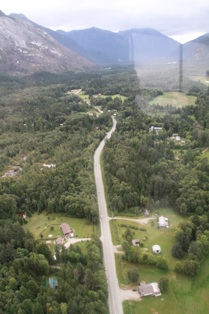 Aerial view of a highway traveling through a small town, towards a mountain range.