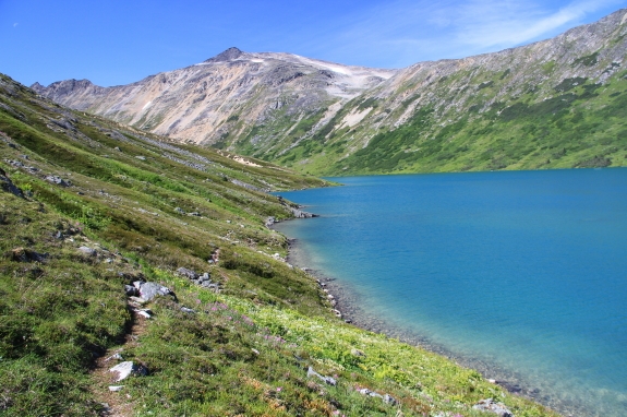 A small lake nestled at the base of a mountain range.