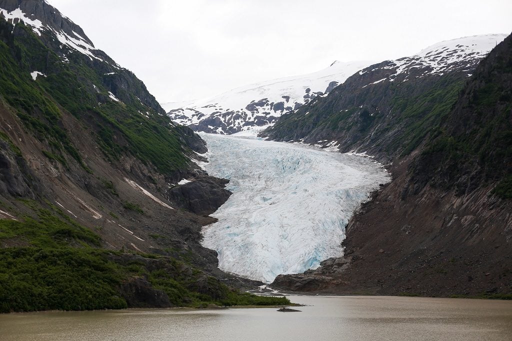 An ancient glacier between two snow-covered mountains.