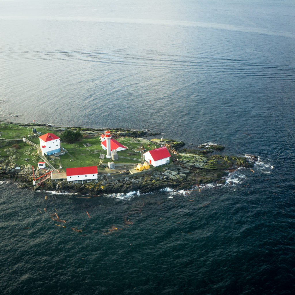 Aerial of a small island dotted with white buildings with red roofs.
