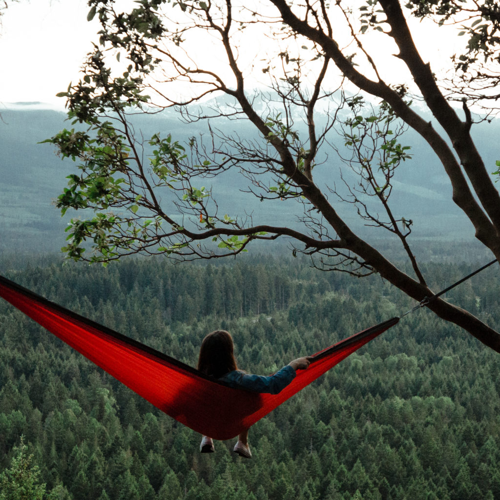 A woman relaxes in a hammock, enjoying views of the forest.