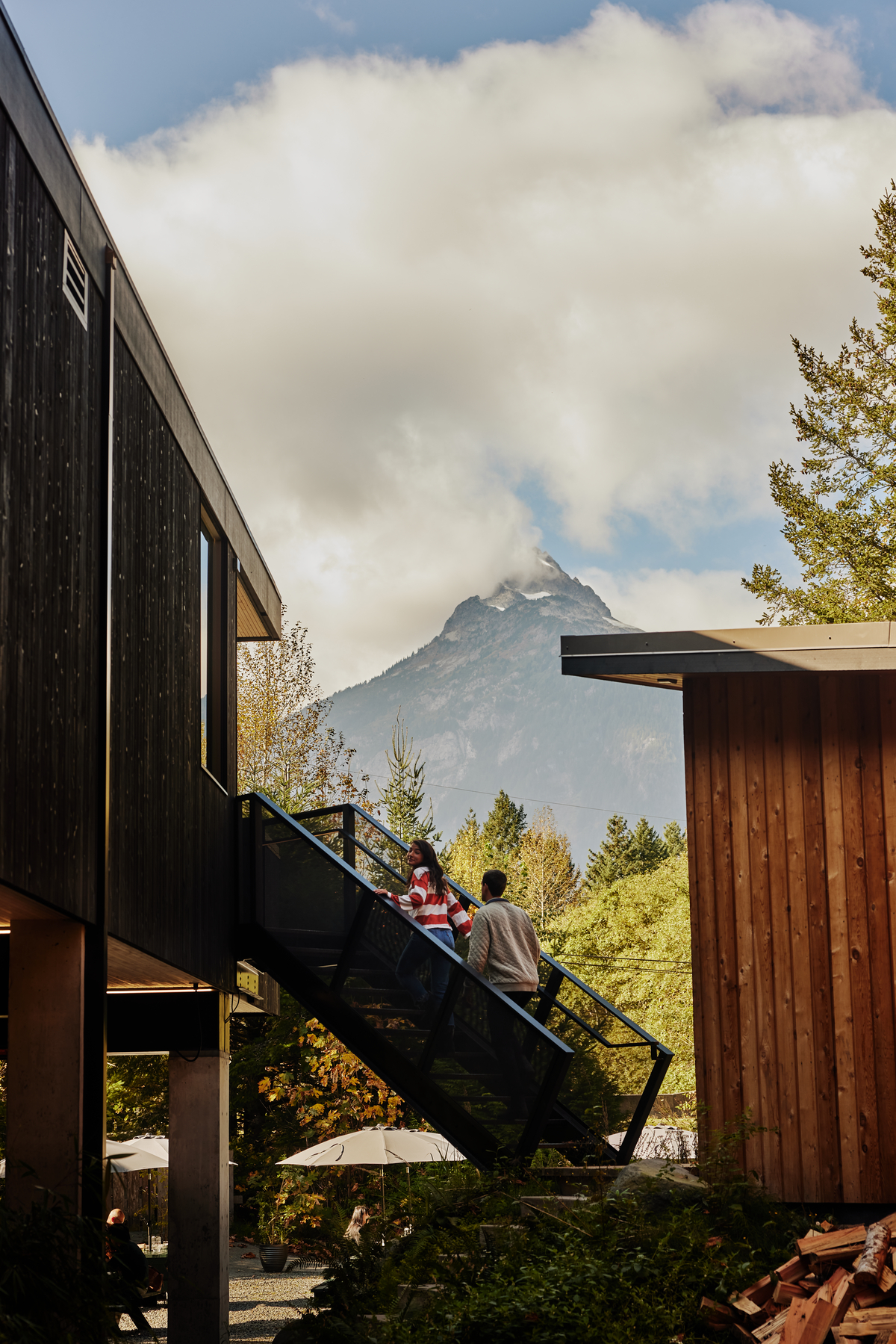 A couple is walking up the metal stairs at Fergie's Cafe in Squamish and taking in the mountain backdrop.