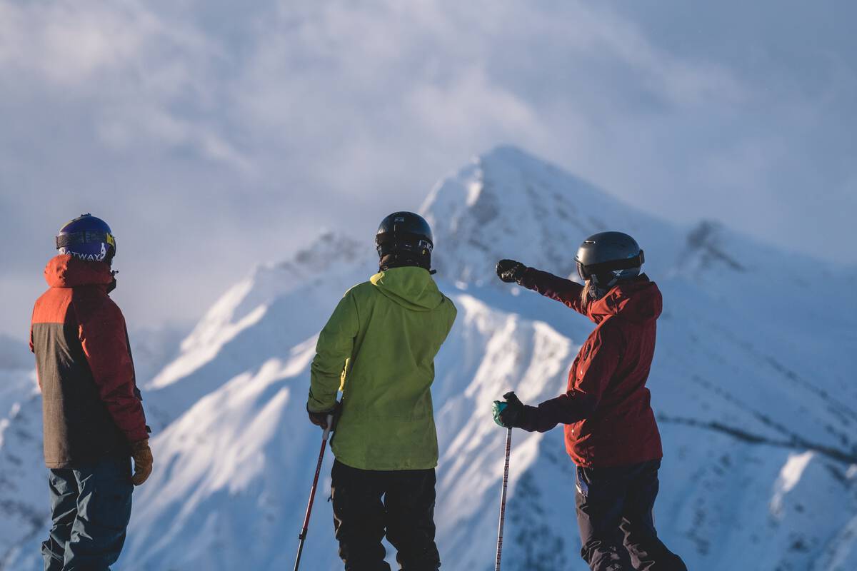 A trio of skiers and snowboarders taking in the view from a mountaintop at Kicking Horse Mountain Resort | Reuben Krabbe