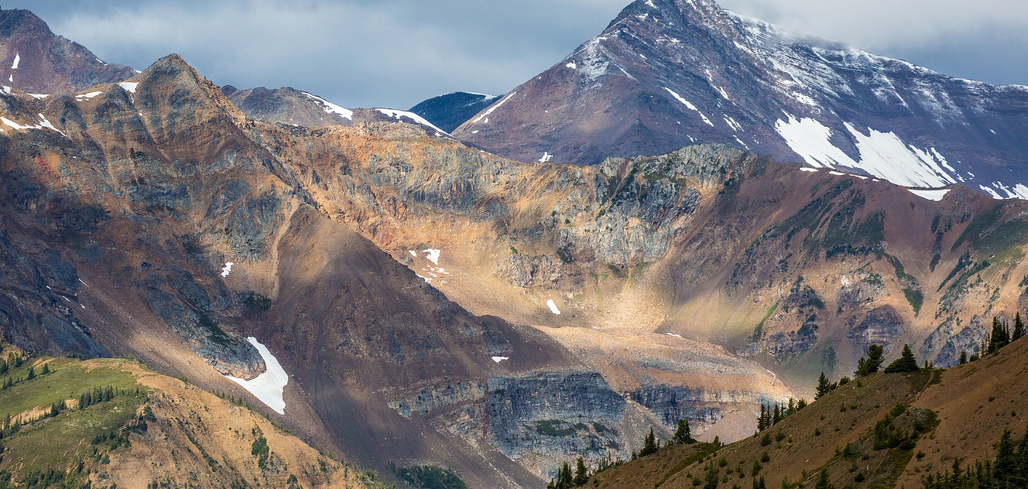 Craggy mountain peaks with sparse trees and patches of ice.