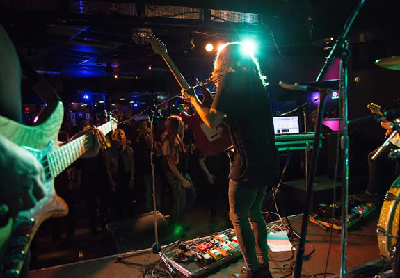 A band plays live onstage at a busy bar.