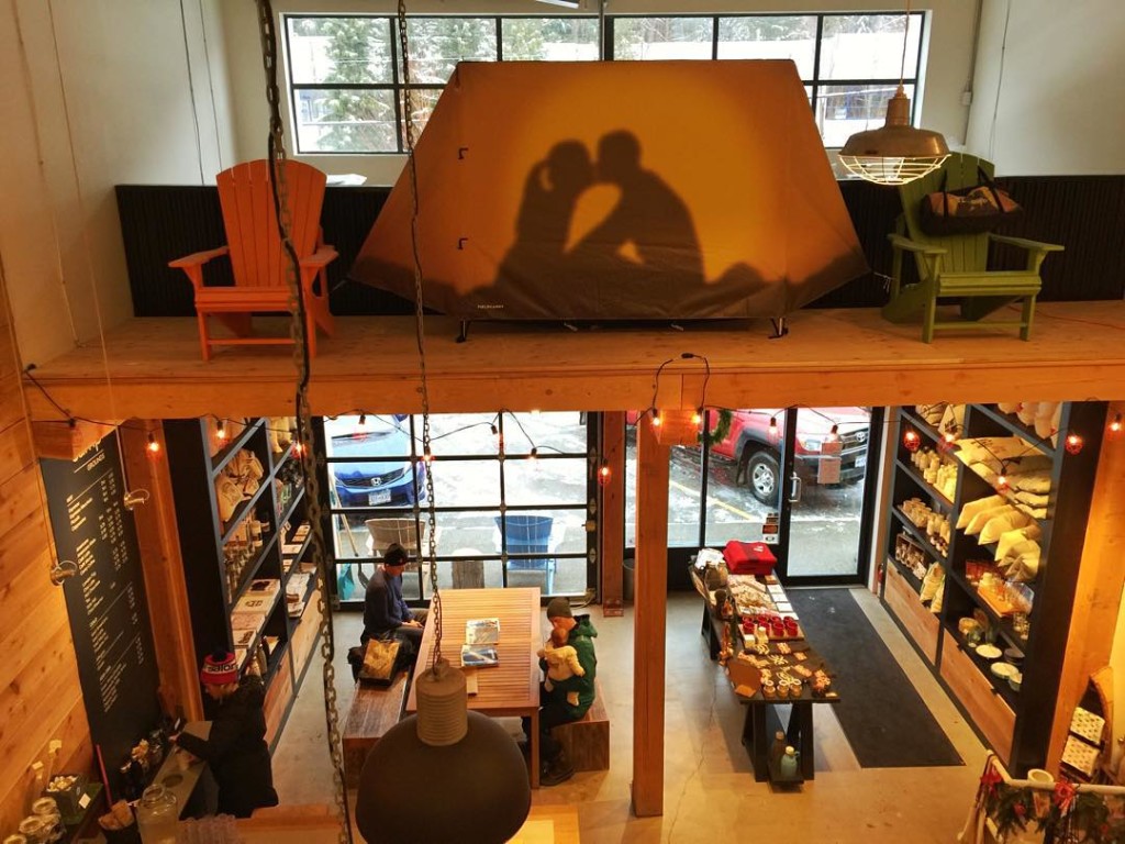 A cozy coffee shop with a tent set up on a ledge, displaying a silhouette of a kissing couple.