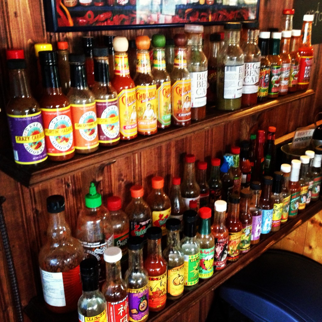 Two shelves filled with different varieties of hot sauce.