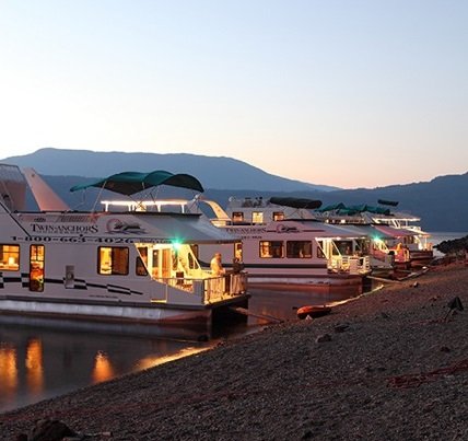 An array of houseboats anchored at the beach at sunset.