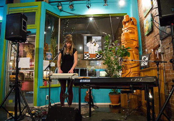 A woman plays keyboard in an eclectic cafe.