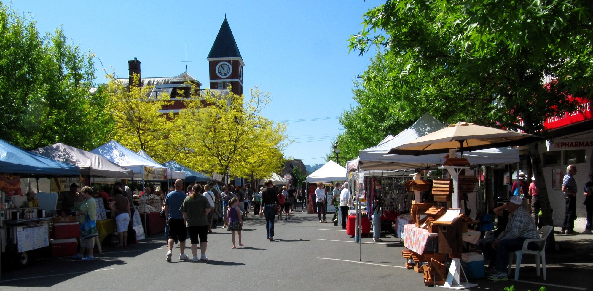An outdoor market is set up on a sunny city street.