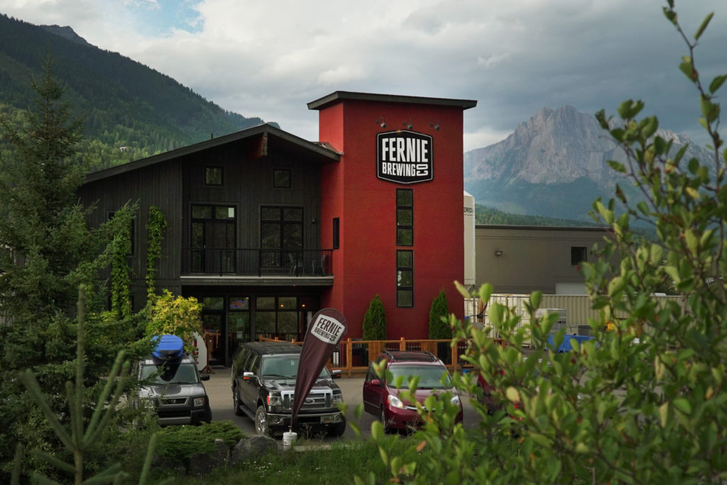 The exterior of the FE]ernie Brewing Co. building, with mountains in the background.