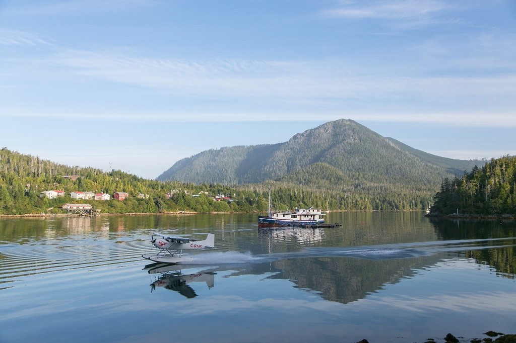 A float plane lands on the calm waters of a small harbour.