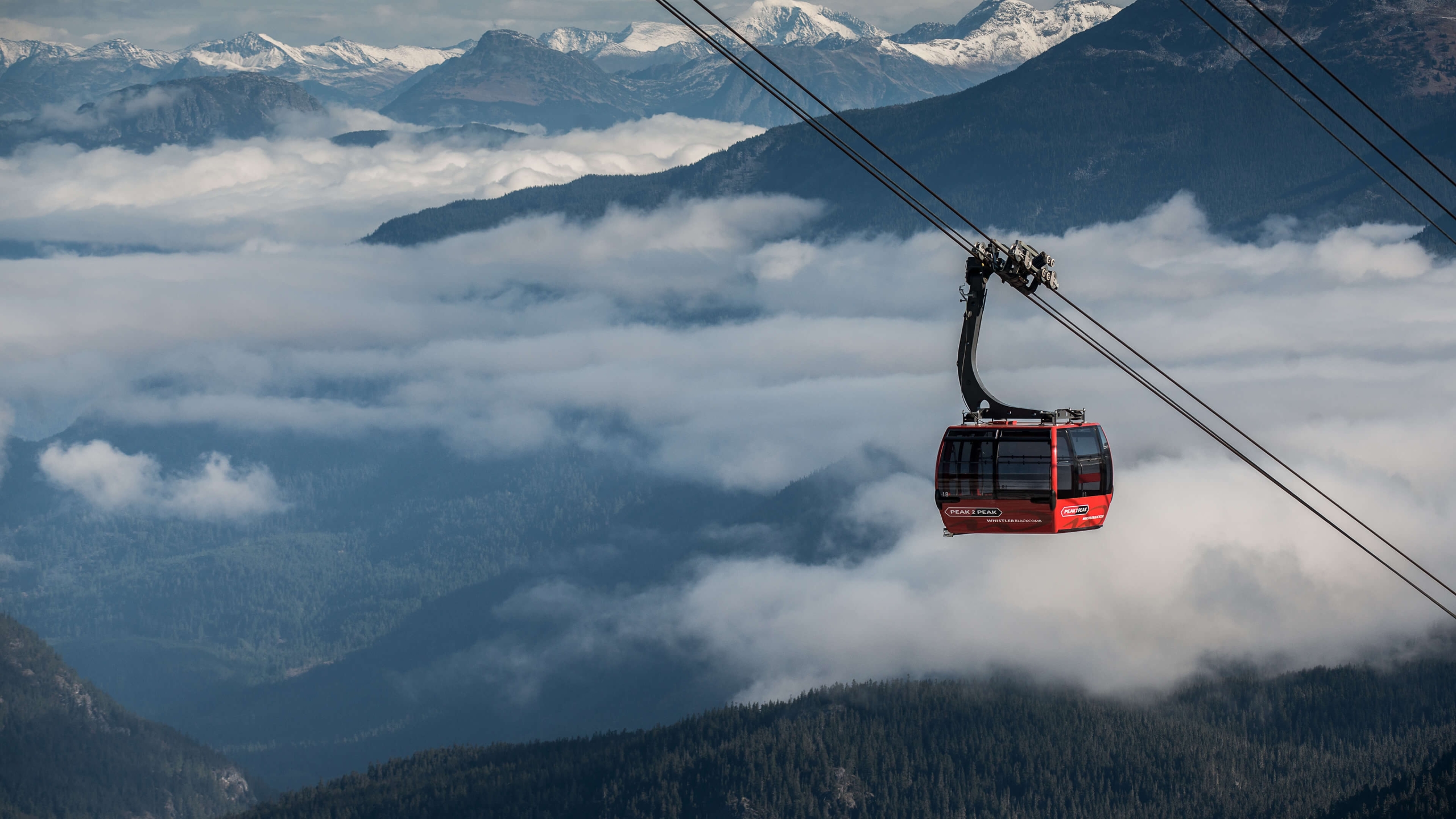 PEAK 2 PEAK Gondola traveling above Whistler, British Columbia. The red gondola is above the clouds and the trees. 