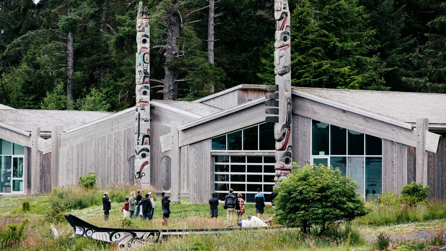 An outside view of the Haida Heritage Centre in Skidegate. Several people are gather around the front.