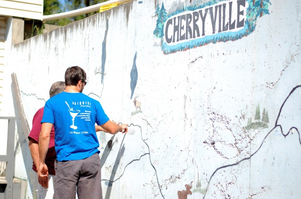 Two men stop to look at a map painted on a wall that says “Cherryville”.