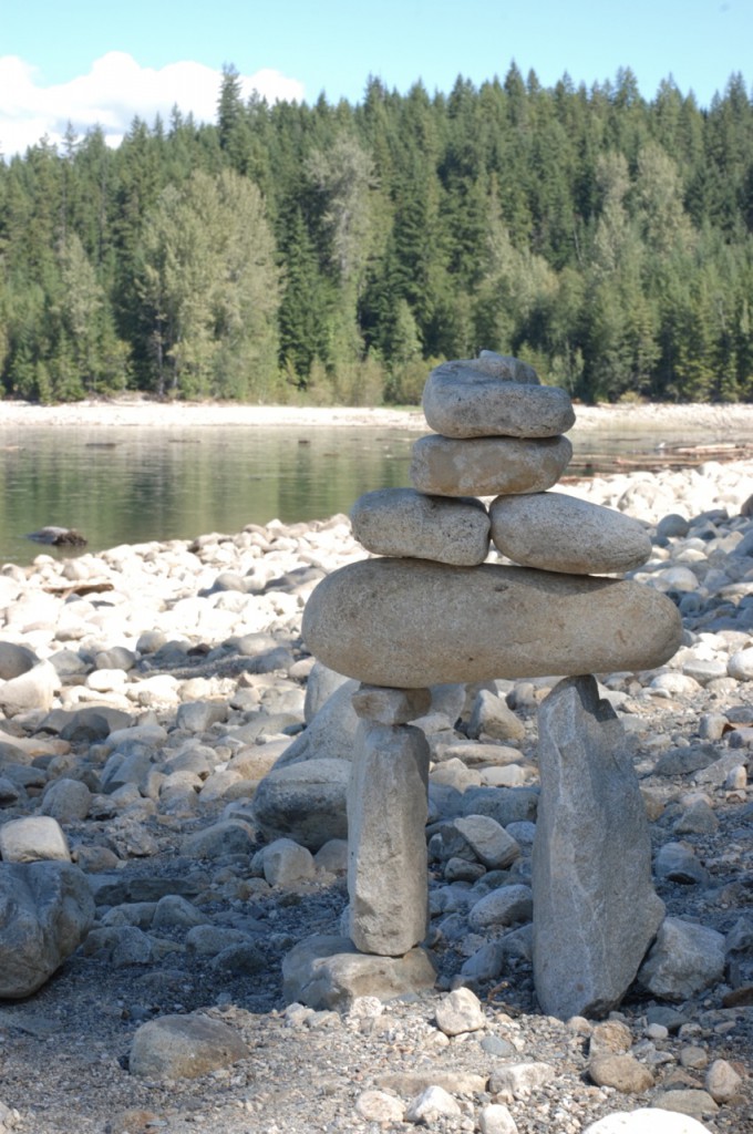 A mini-inukshuk sits on a rocky beach.