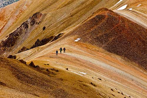 Three hikers walking through the Rainbow Range in Tweedsmuir Provincial Park. 