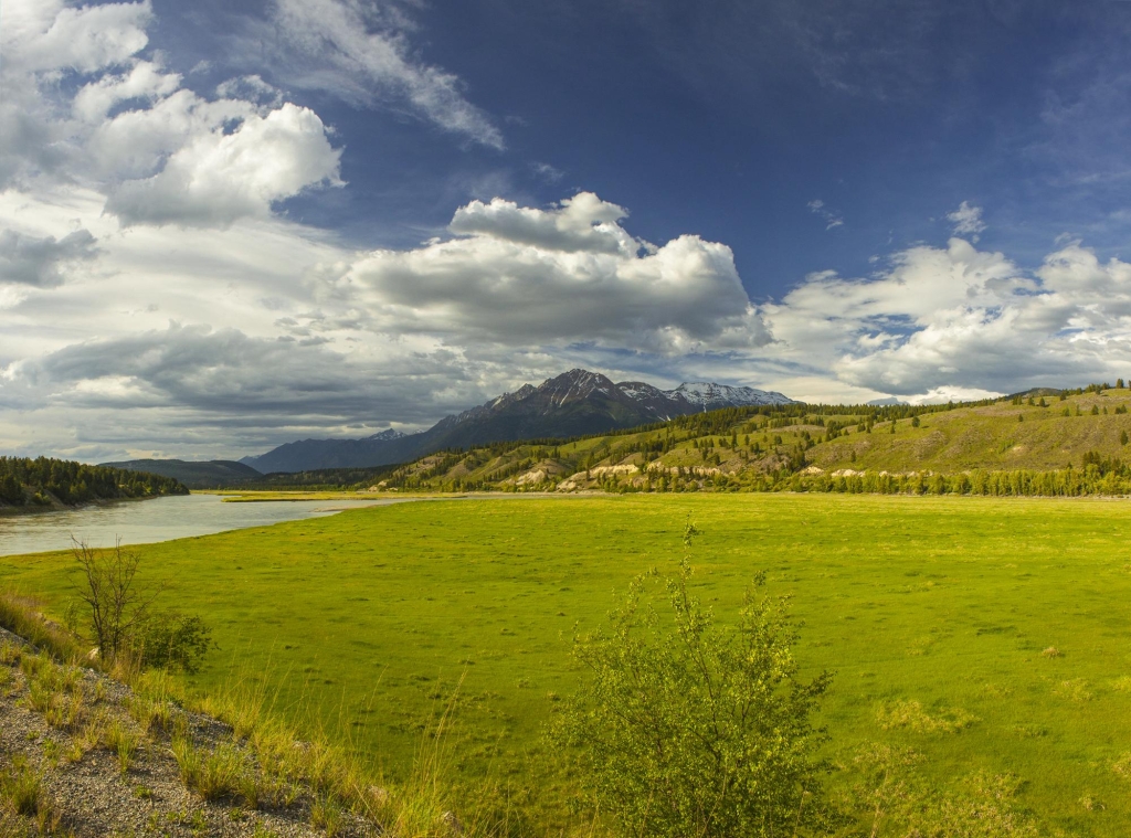 A lush, sprawling landscape is nestled between a river and a mountain range.