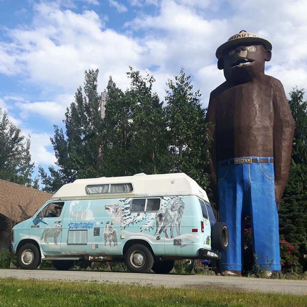A giant statue of Smokey Bear next to a VW wagon.