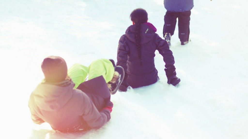 Two people sliding down a hill on their pants