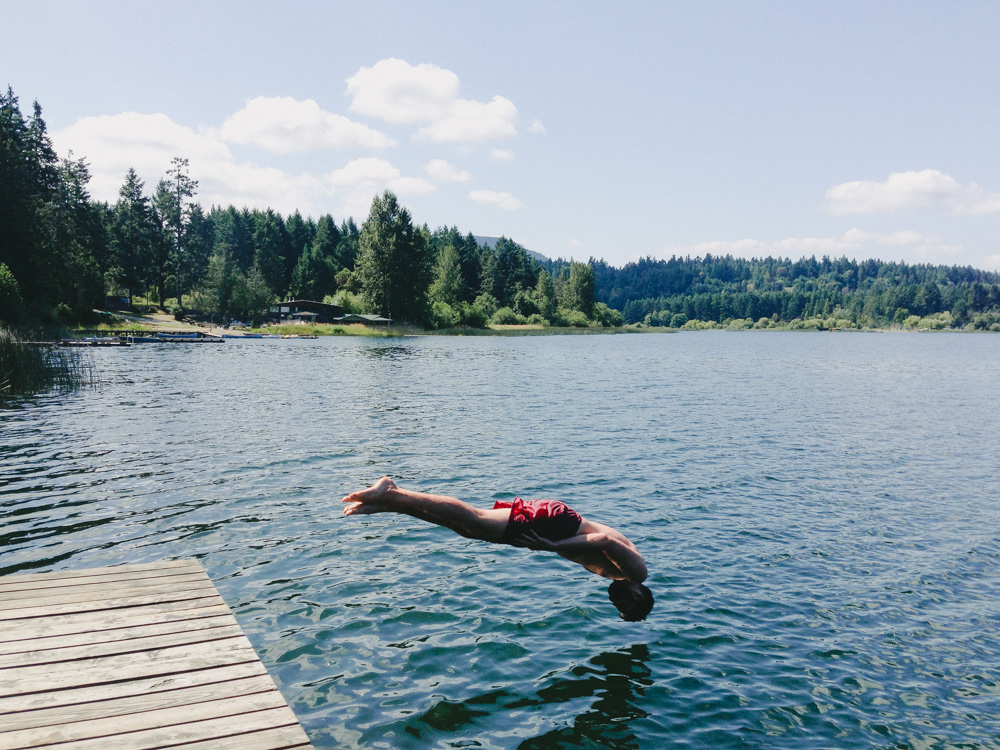 A man dives off a dock into a lake. 