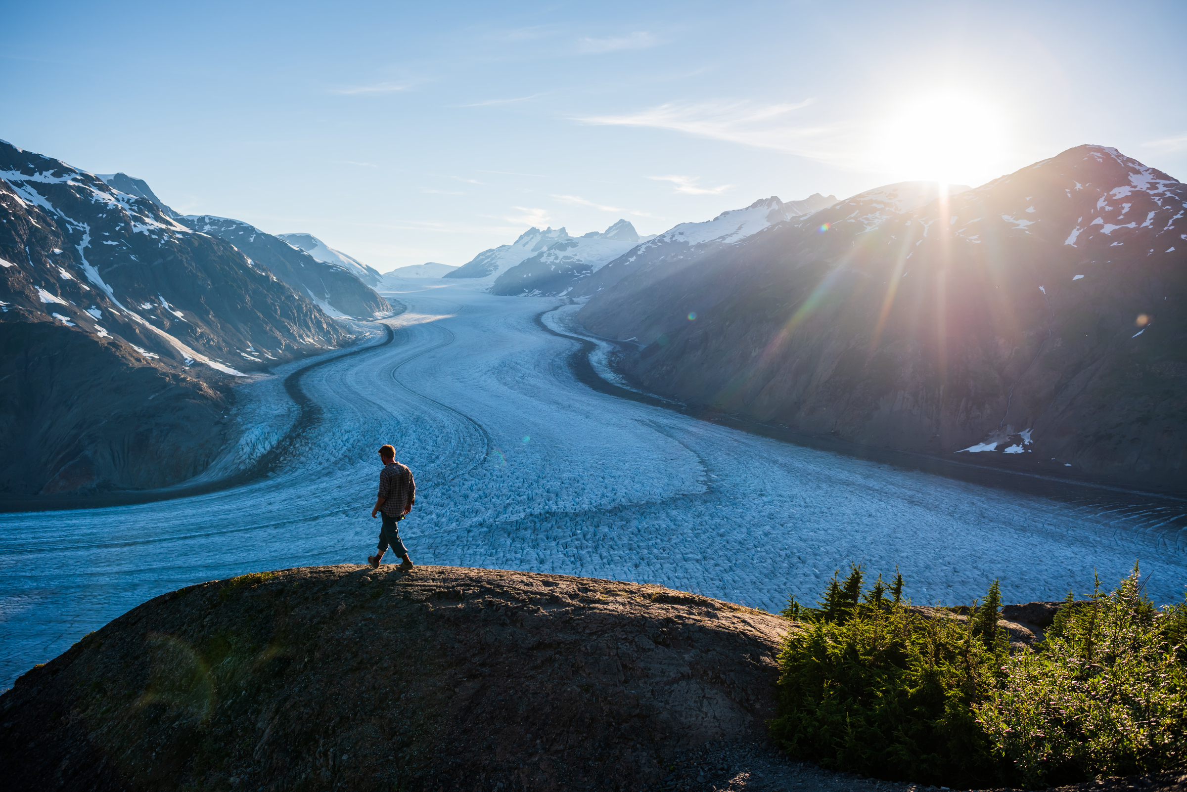 A person stands at a lookout with the vast expanse of Salmon Glacier in the distance. 