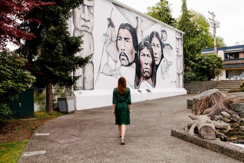 A woman walks over to an outdoor mural of Indigenous People in Chemainus,