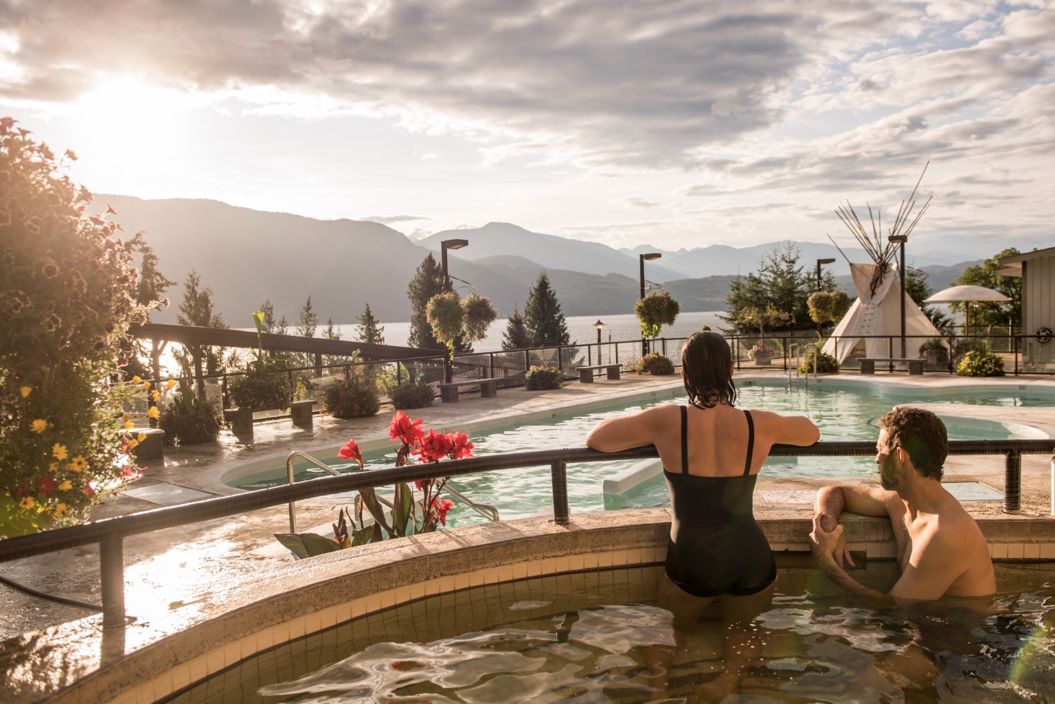 People in a hot spring tub looking out over mountains surrounding Kootenay Lake.