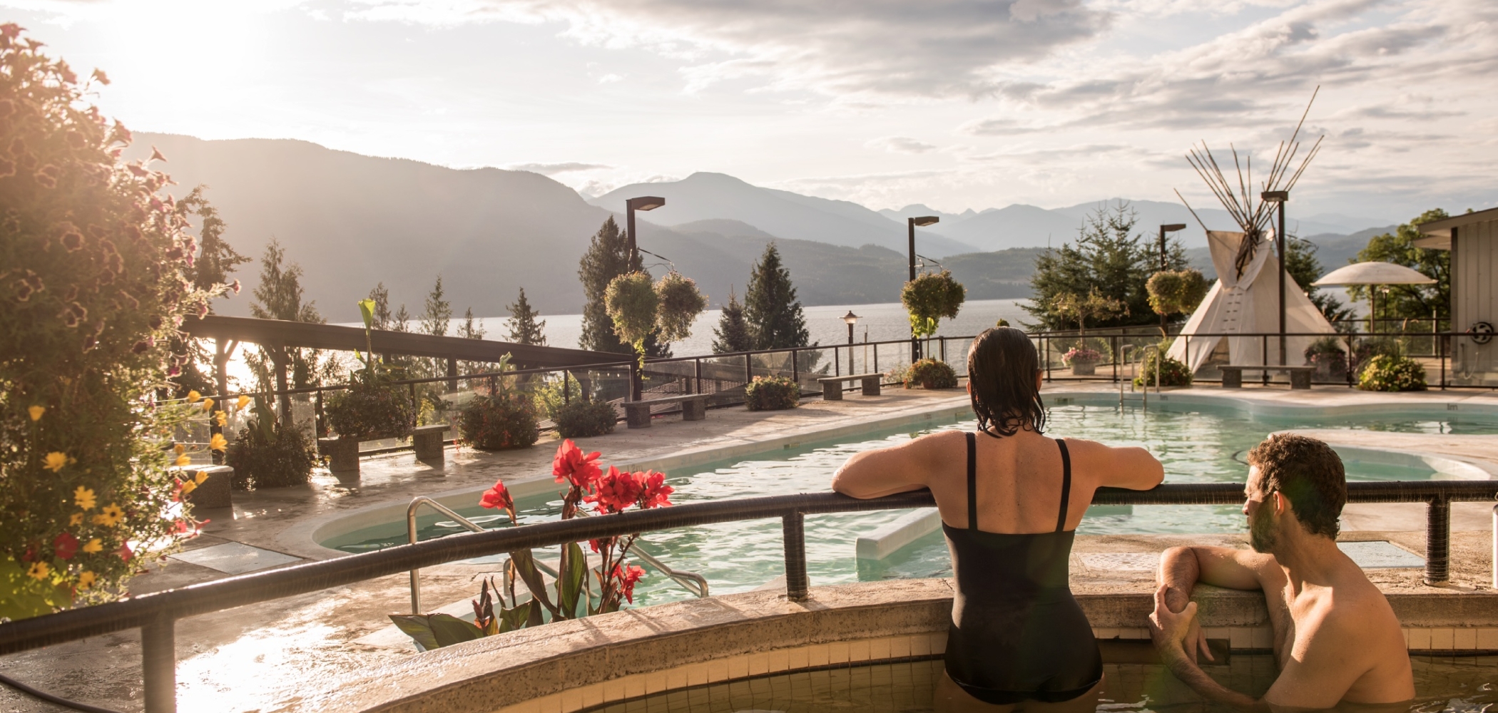 People in a hot spring tub looking out over mountains surrounding Kootenay Lake.