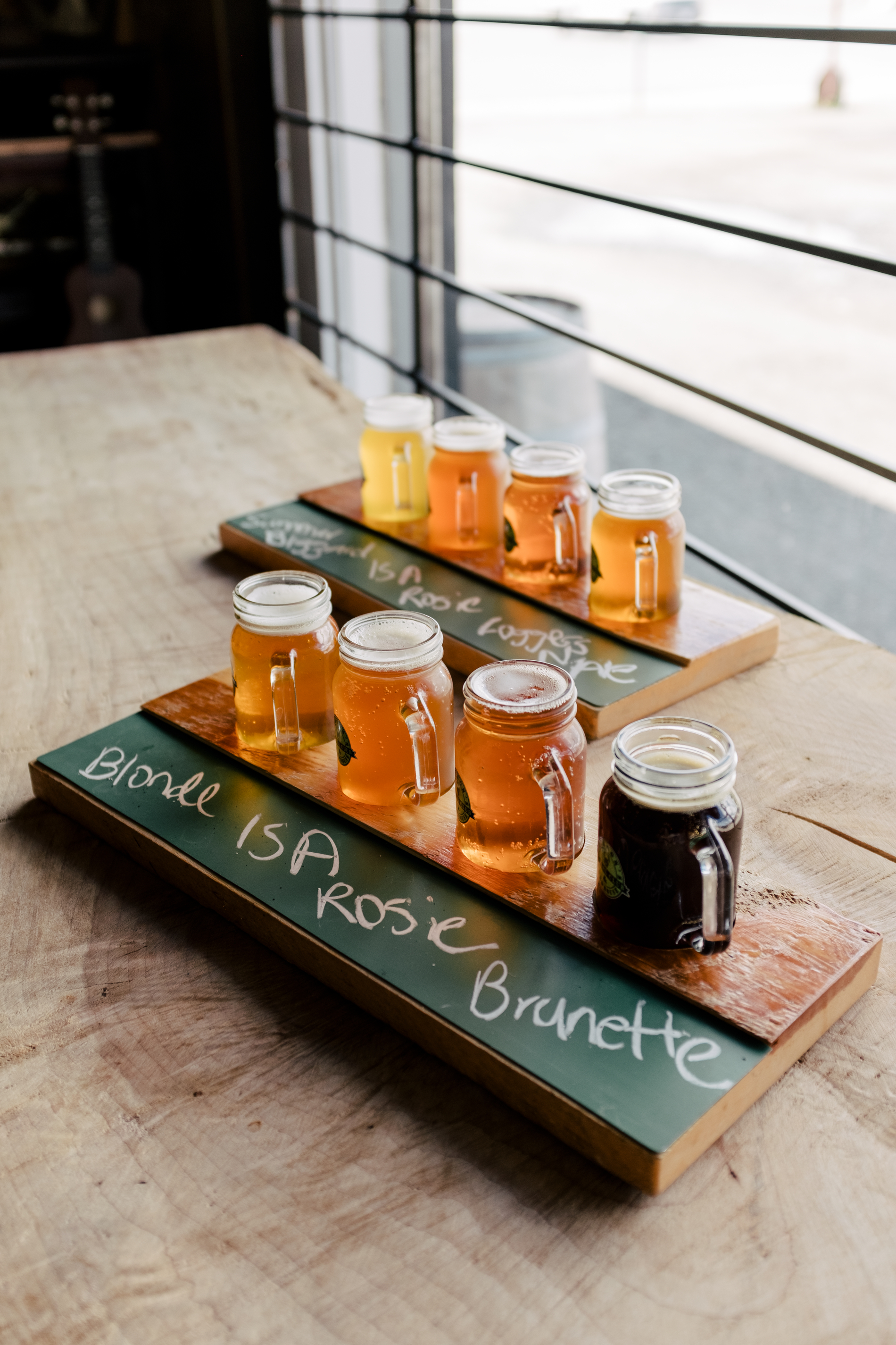 Two flights of beer with four small beers on wooden planks, placed on a table at Jackson's Social Club & Brewhouse in 100 Mile House